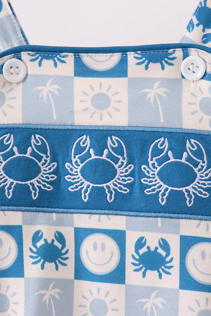 Detail of blue-and-white checkered baby romper with crab embroidery and button placket