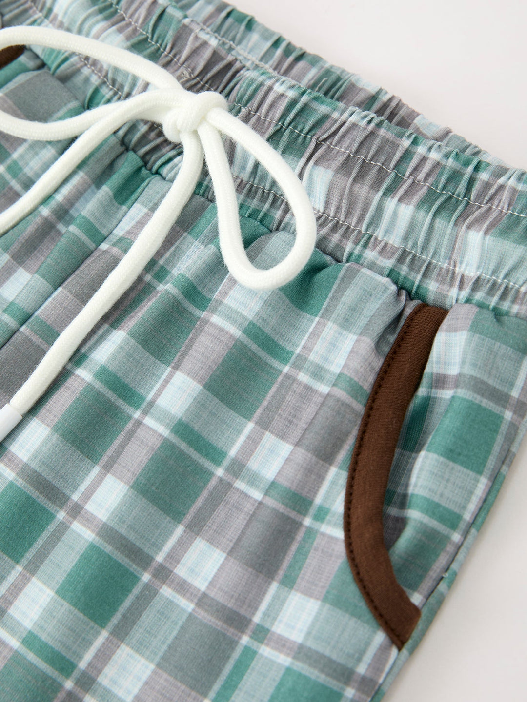 Green plaid pull-on pants with elastic waistband and white drawstring, brown trim