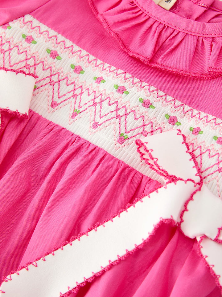 Hot pink romper detail: zigzag smocked embroidery and lace trim across yoke