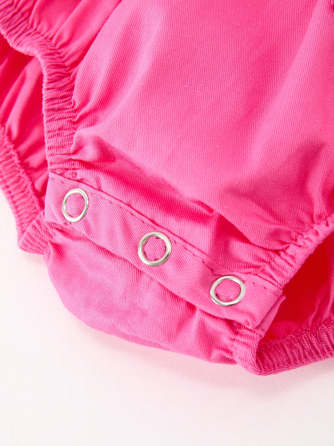 Hot pink romper close-up of leg opening with snap buttons and gathered cuffs