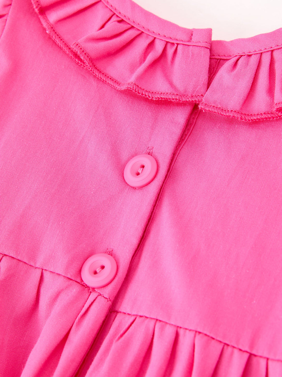 Hot pink romper close-up of button placket and ruffled neckline