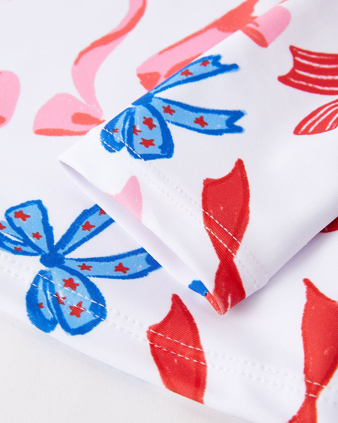 Close-up of fabric with red fish and blue bows pattern on a white background