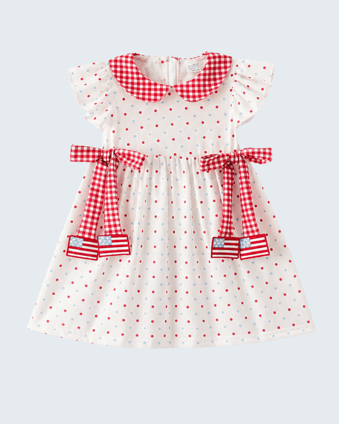 White dress with red polka dots and checkered details on a light gray background