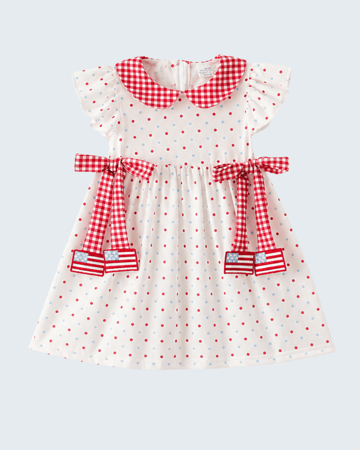 White dress with red polka dots and checkered details on a light gray background