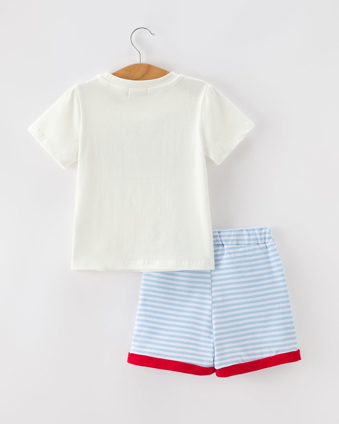White t-shirt and blue striped shorts on a hanger against a white background