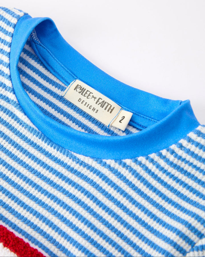 Close-up of a blue and white striped shirt with a brand label on a white background