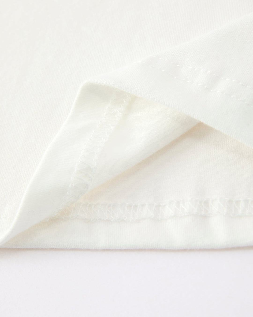 Close-up of a white fabric with a subtle pattern on a light gray background
