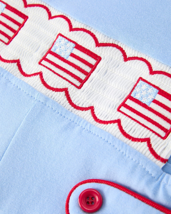 Close-up of a light blue fabric with red and white embroidered designs and a button.