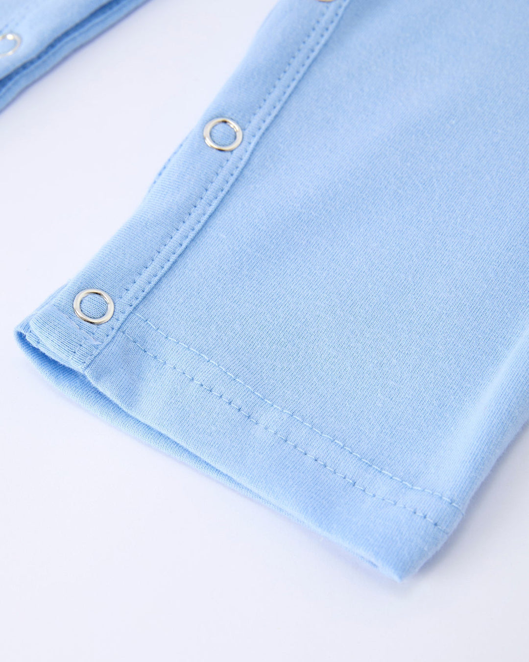 Close-up of light blue fabric with gold buttons on a white background