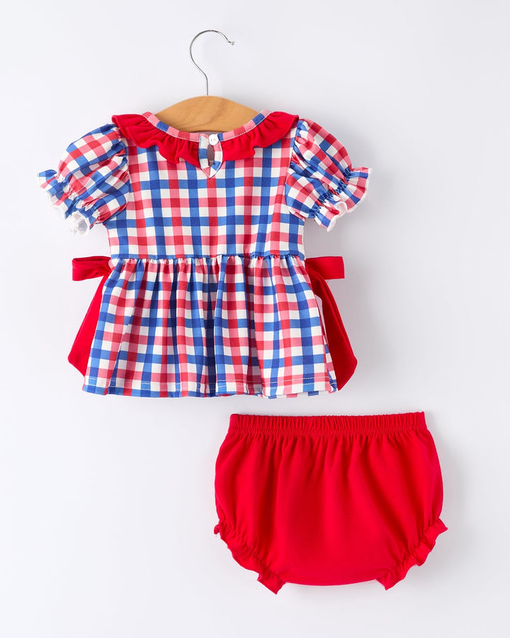 Red, white, and blue checkered top with matching bloomers on a hanger against a white background