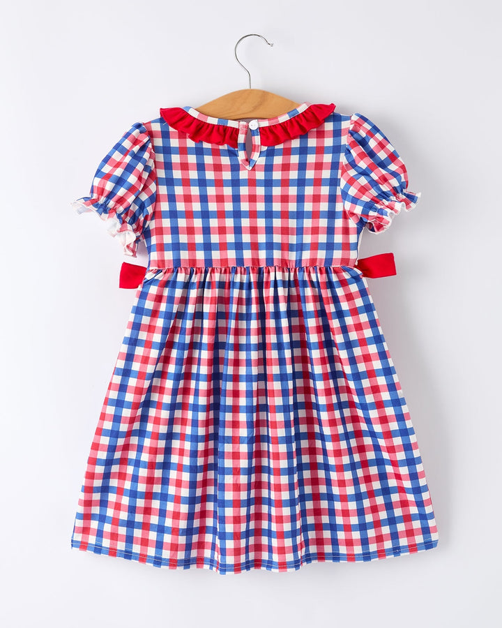 Red, white, and blue checkered dress on a hanger against a white background