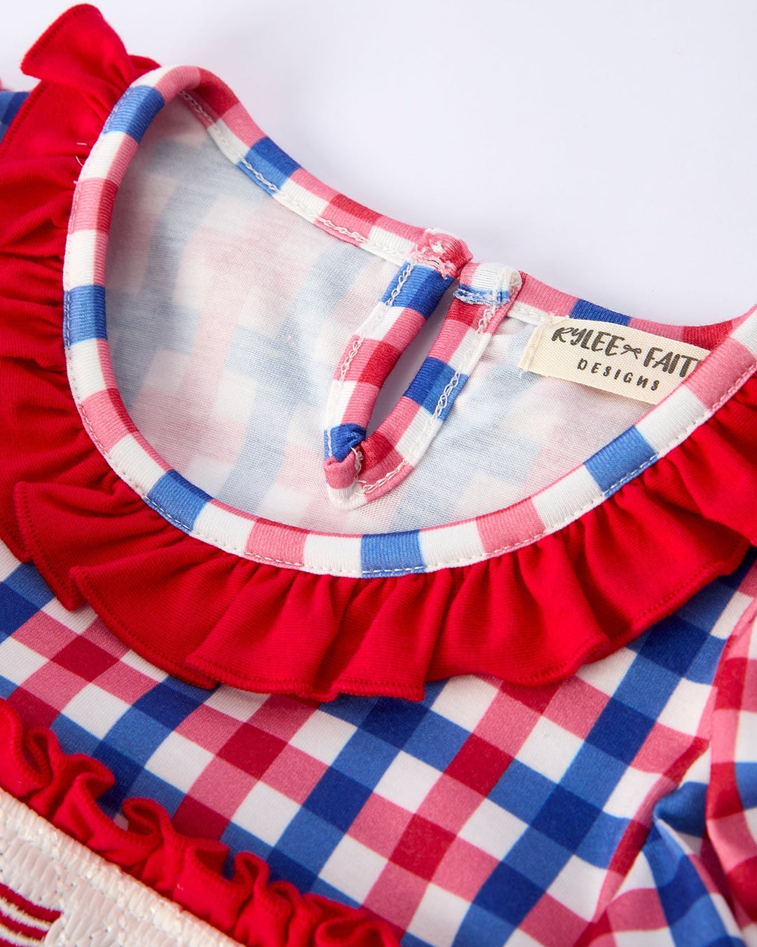 Red, white, and blue checkered dress with ruffled collar and neckline.