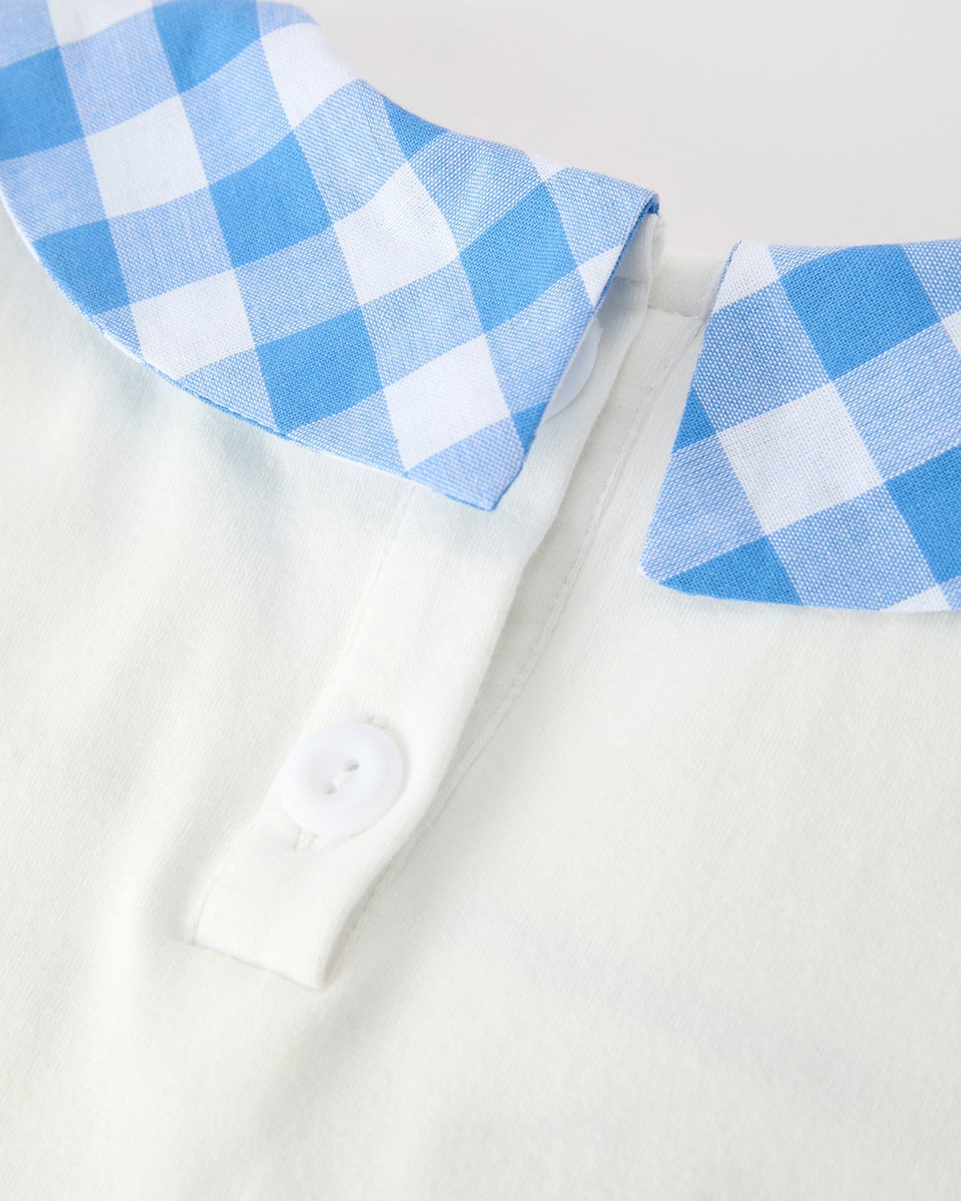White shirt with blue and white checkered collar and cuffs on a light gray background