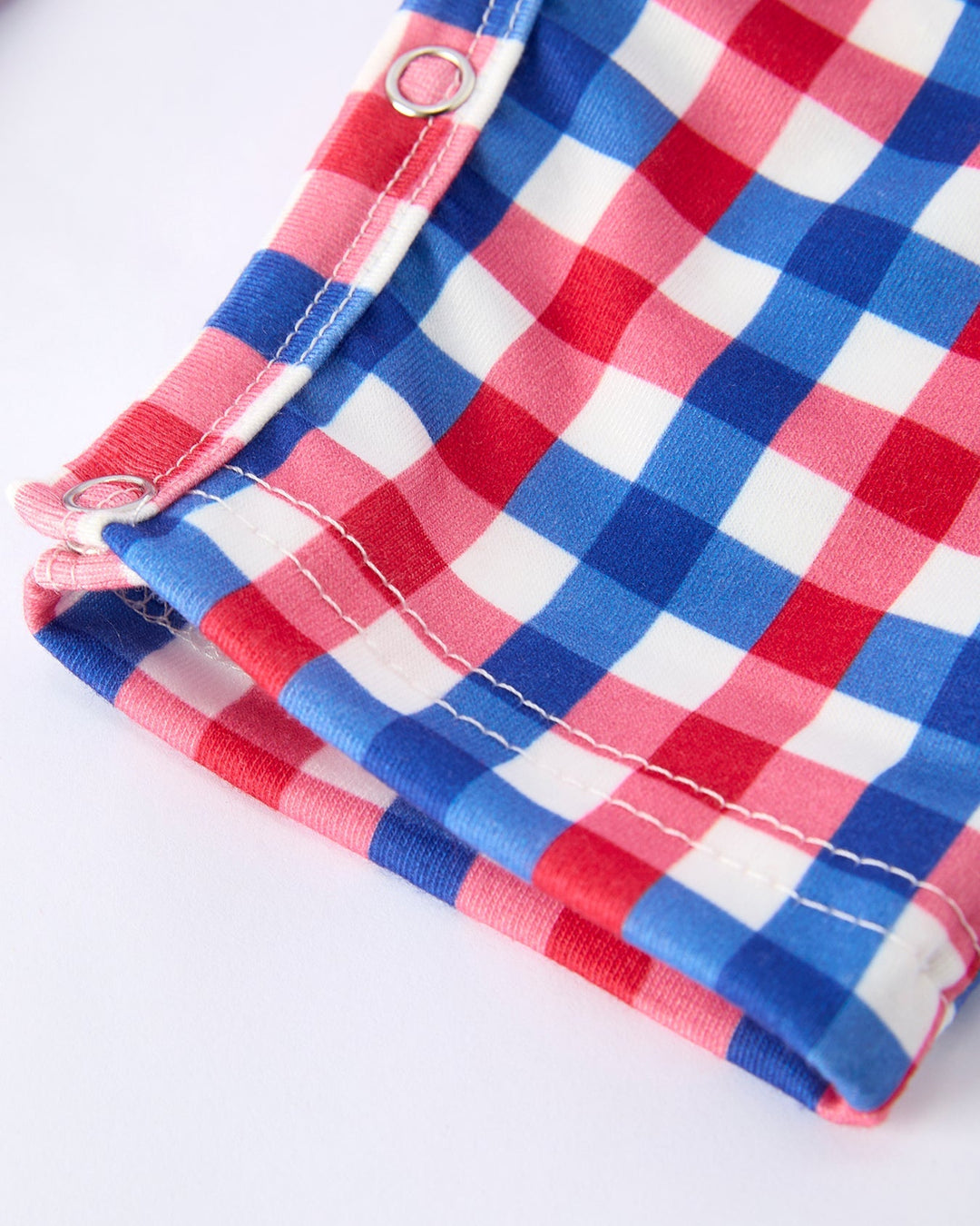 Red, white, and blue checkered fabric with a metal grommet on a white background
