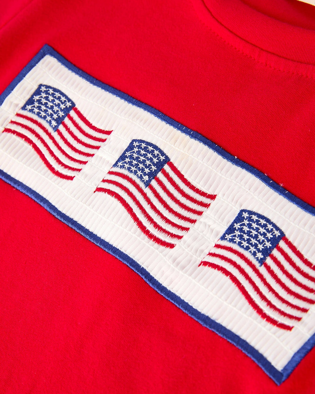 Red shirt with embroidered American flags on a white background