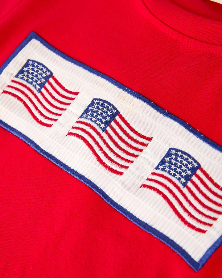 Red shirt with embroidered American flags on a white background