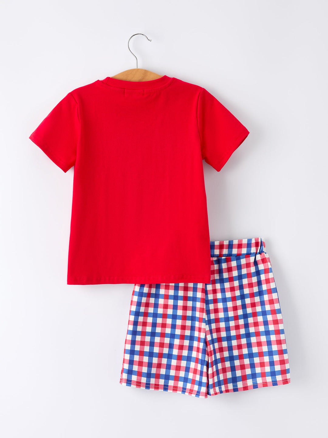 Red t-shirt and red, white, and blue checkered shorts on a hanger against a white background