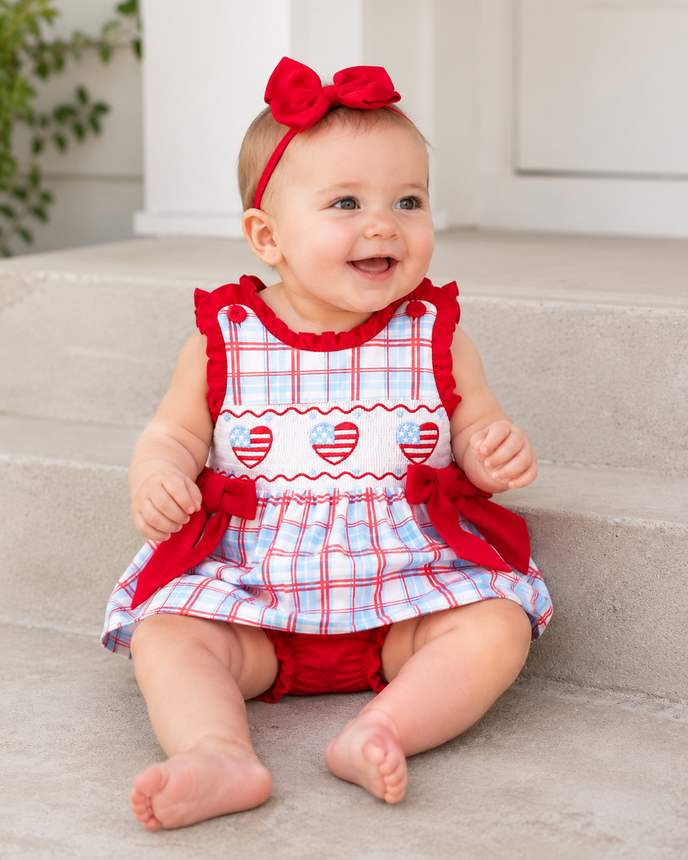 Baby girl sitting on stairs wearing 4th of July Plaid Smocked Bloomer Set