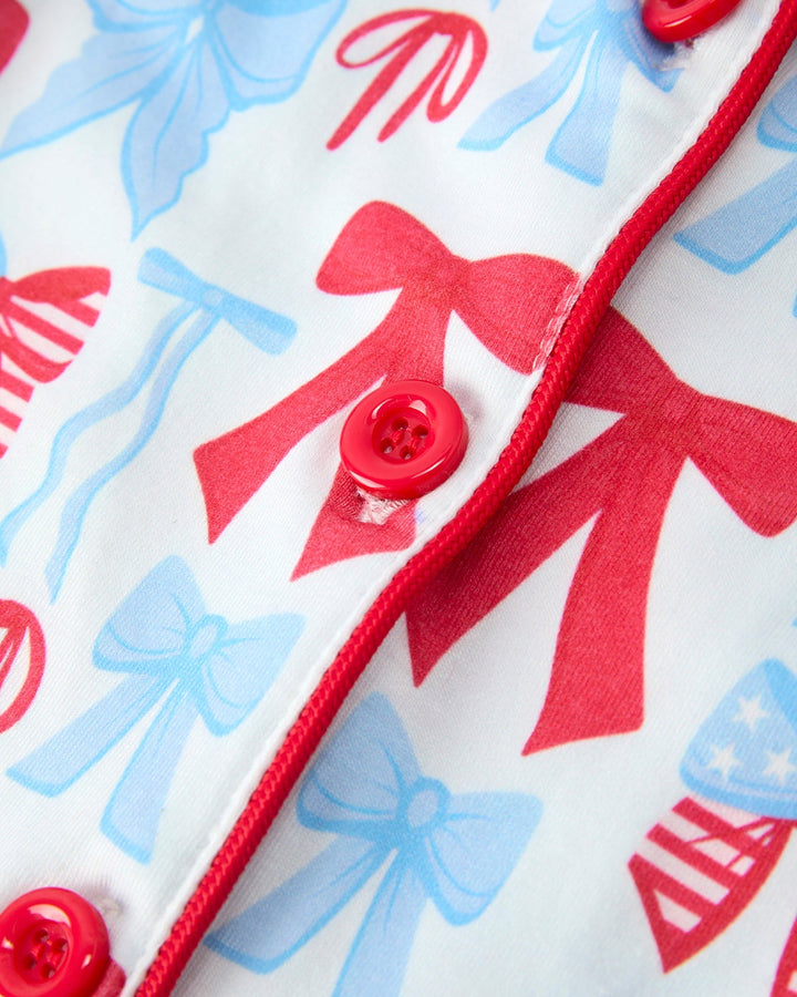 Close-up of a fabric with red and blue bows and buttons on a white background
