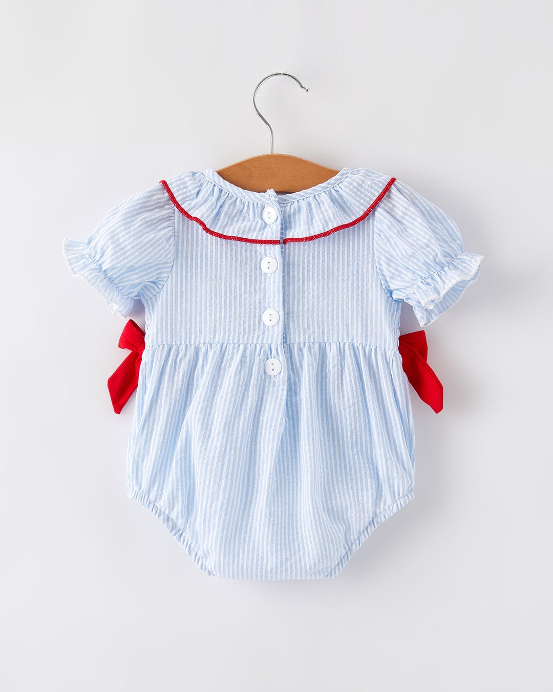 Baby romper with red trim on a hanger against a white background