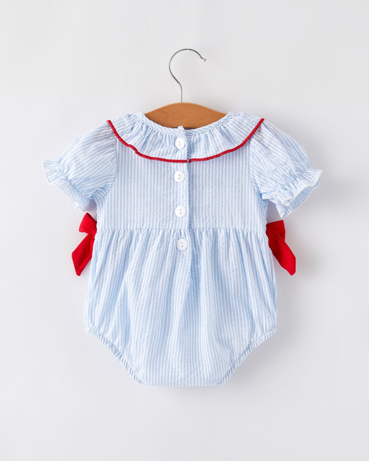 Baby romper with red trim on a hanger against a white background