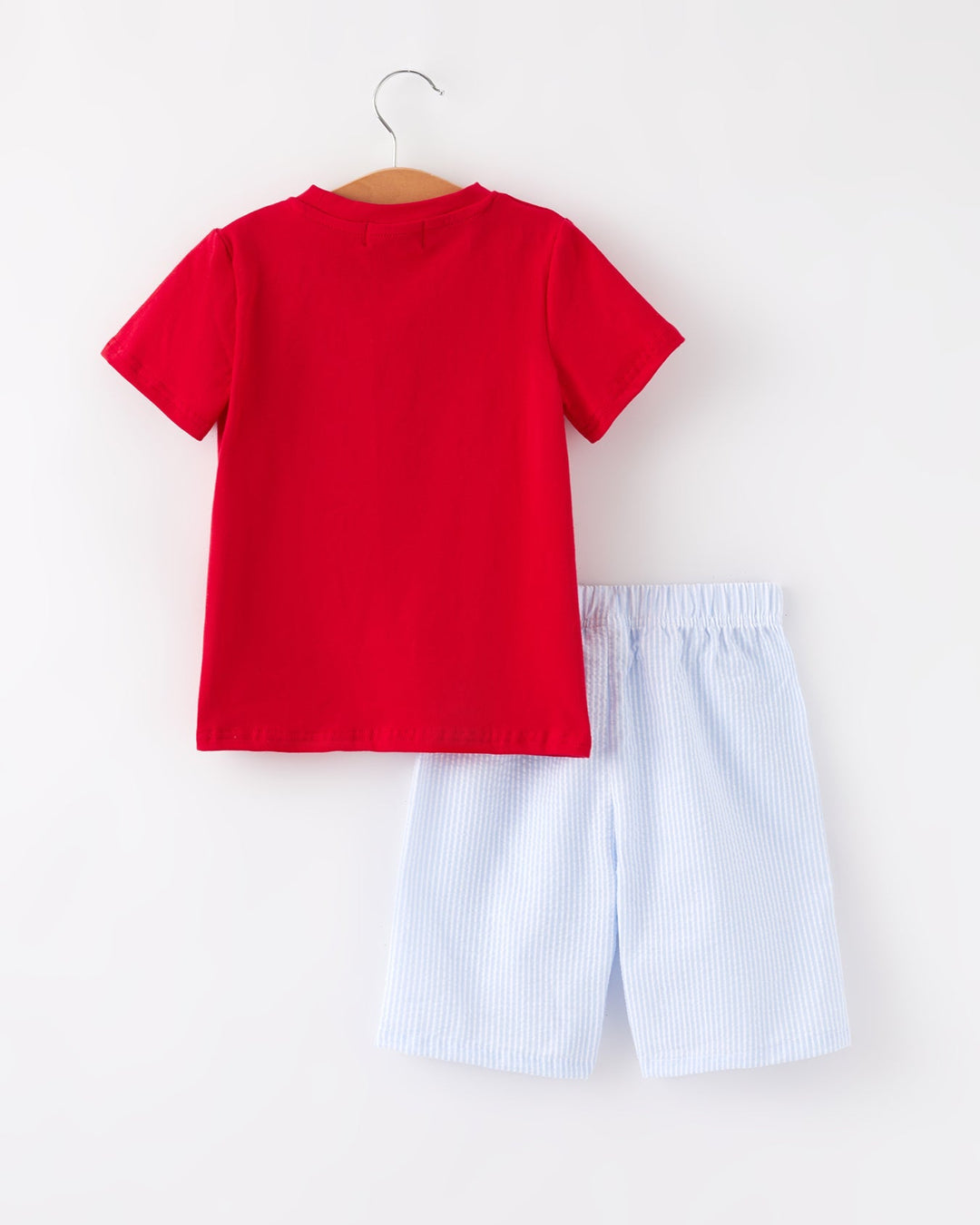 Red t-shirt and light blue shorts on a hanger against a white background