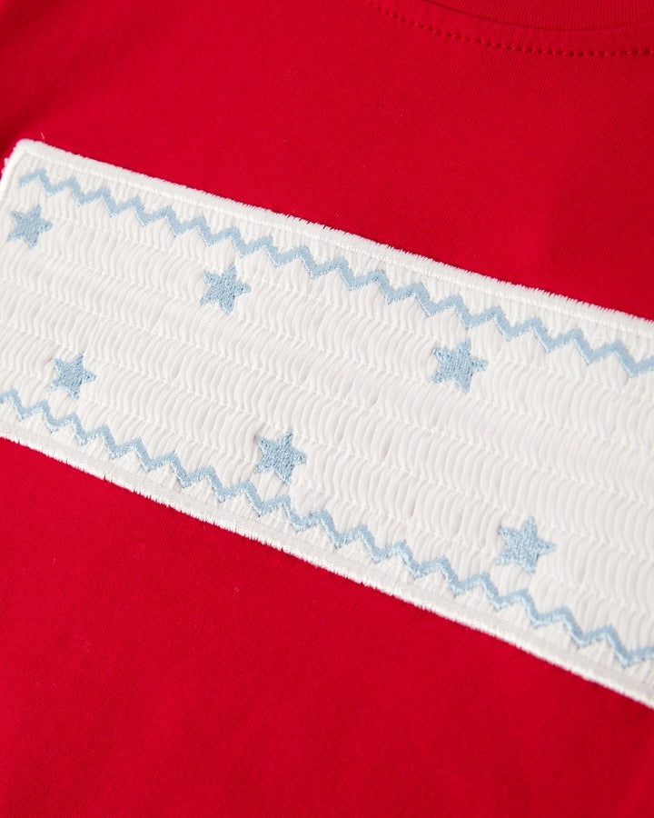Close-up of a red garment with white trim featuring blue star patterns.