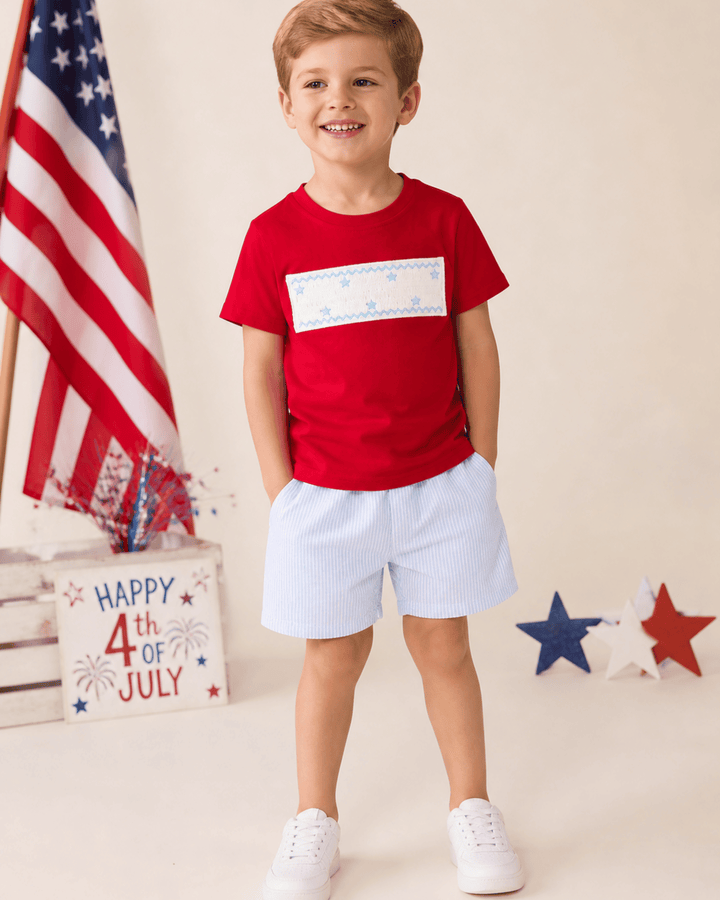 Boy in red shirt and blue shorts celebrating 4th of July