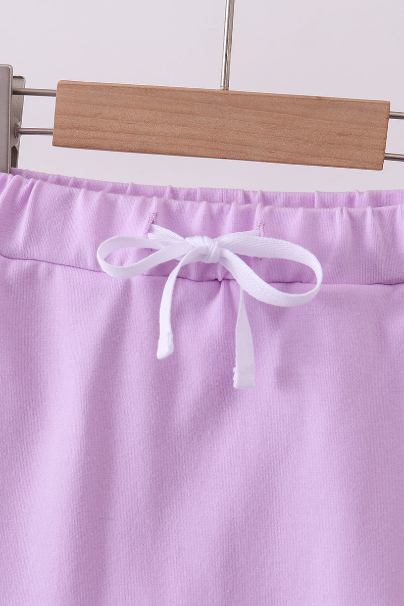 Purple skort with scalloped hem and white bow tie at the waistband