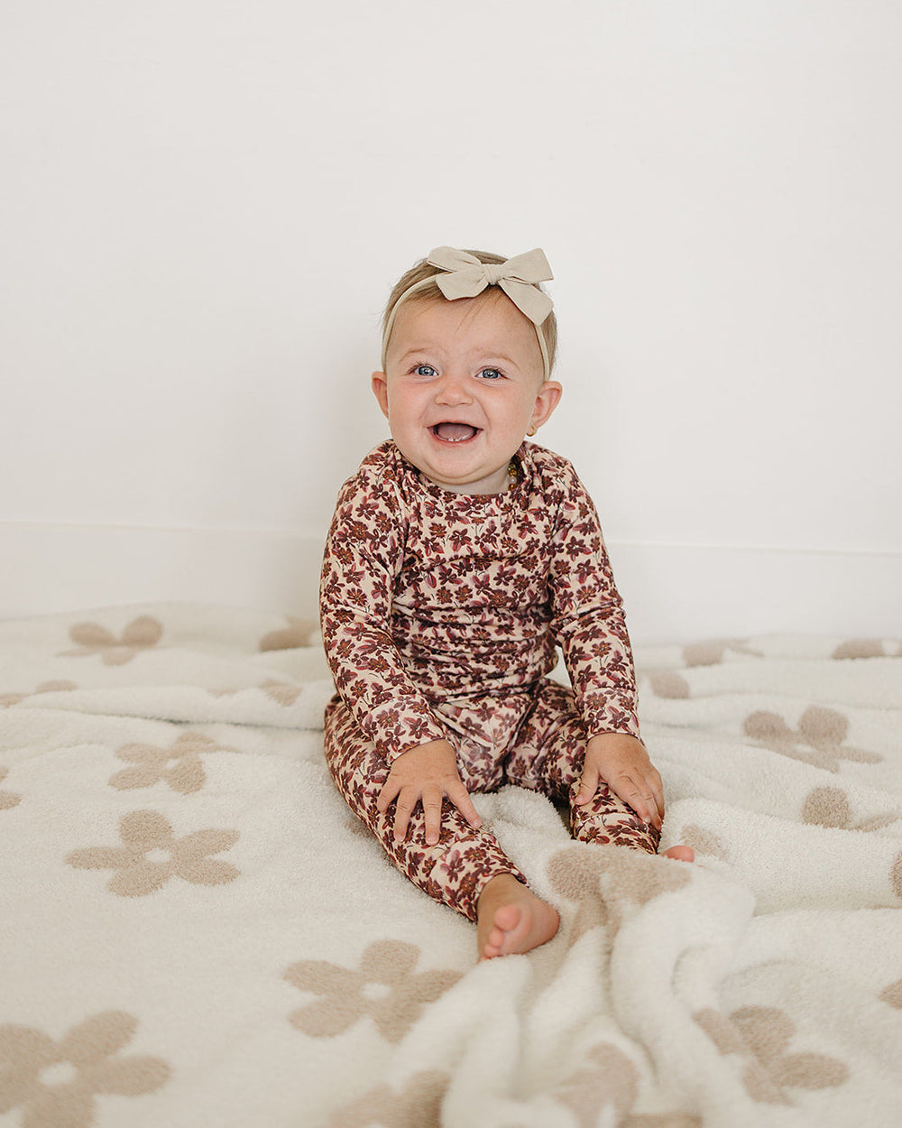 Baby wearing burgundy floral long-sleeve top and matching pants set, seated
