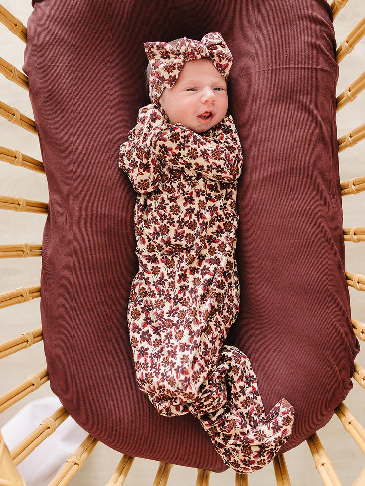 Baby head wrap with all-over dark red and cream floral print, bow-knotted top