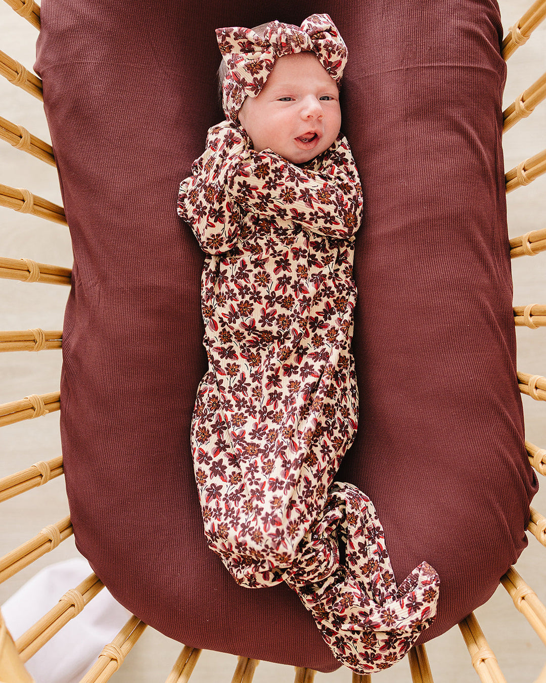 Floral knot baby gown worn by baby, long sleeves, footed, maroon and cream print