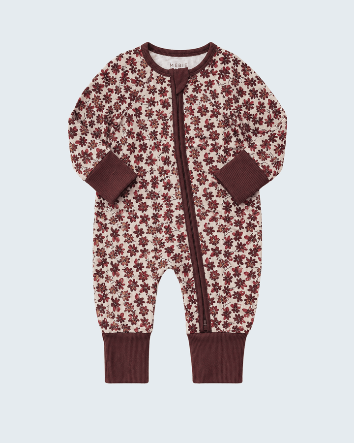 A baby one-piece footless sleeper with a brown and cream floral pattern, featuring a front zipper, long sleeves, and ribbed cuffs and collar, shown on a light gray background.