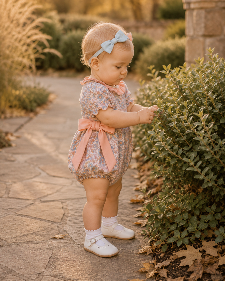 Multicolor floral smocked romper with ruffled collar, bow ties, and short sleeves