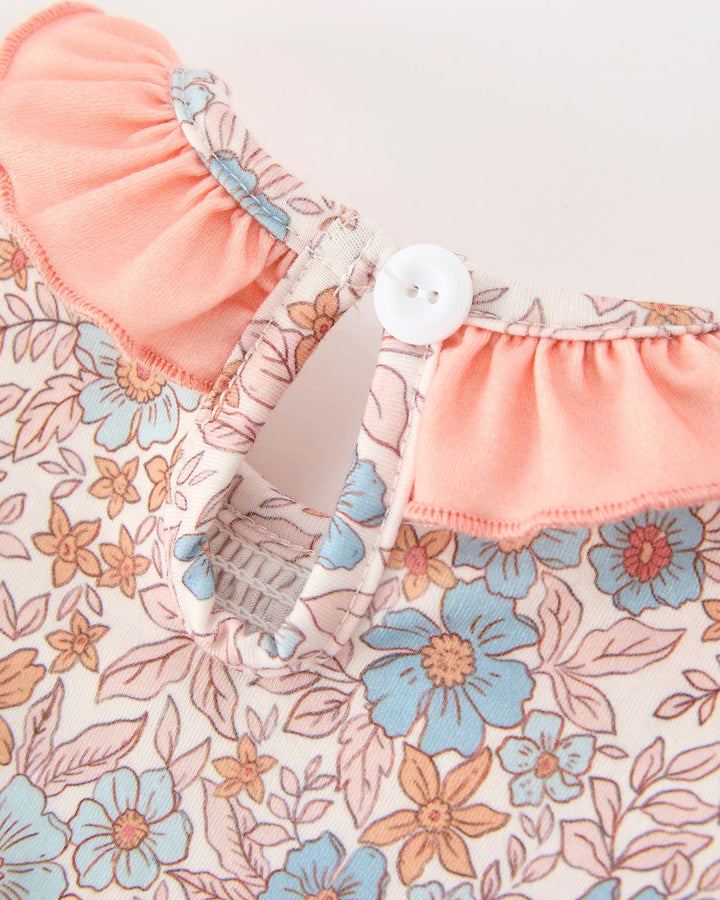 Floral baby romper with pink yoke, button shoulder closure and gathered ruffle neck