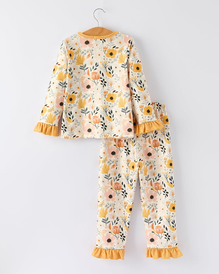 Girls pajama set in cream floral print with orange long sleeves and ruffled cuffs; pants with cuffs