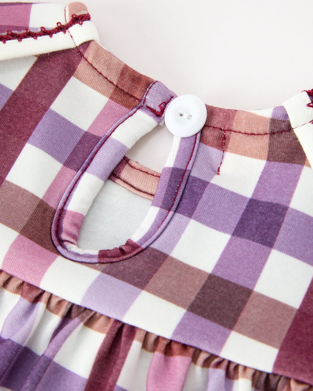 Girls plaid dress neckline with round button, stitched trim, and gathered waist