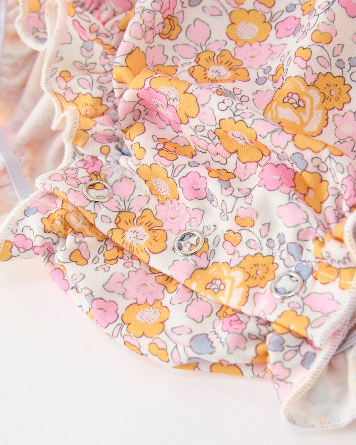 Baby floral romper with pink, orange, and yellow flower print and yellow-trim hem