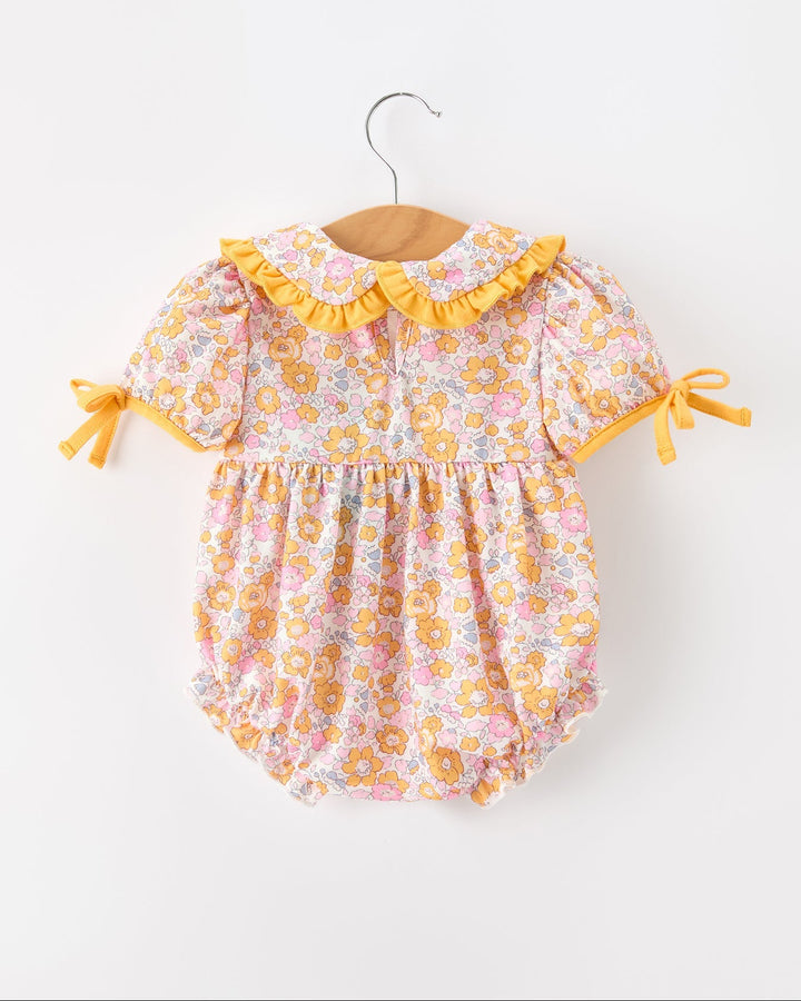 Baby floral romper with yellow ruffle trim, bow ties on sleeves, snap legs