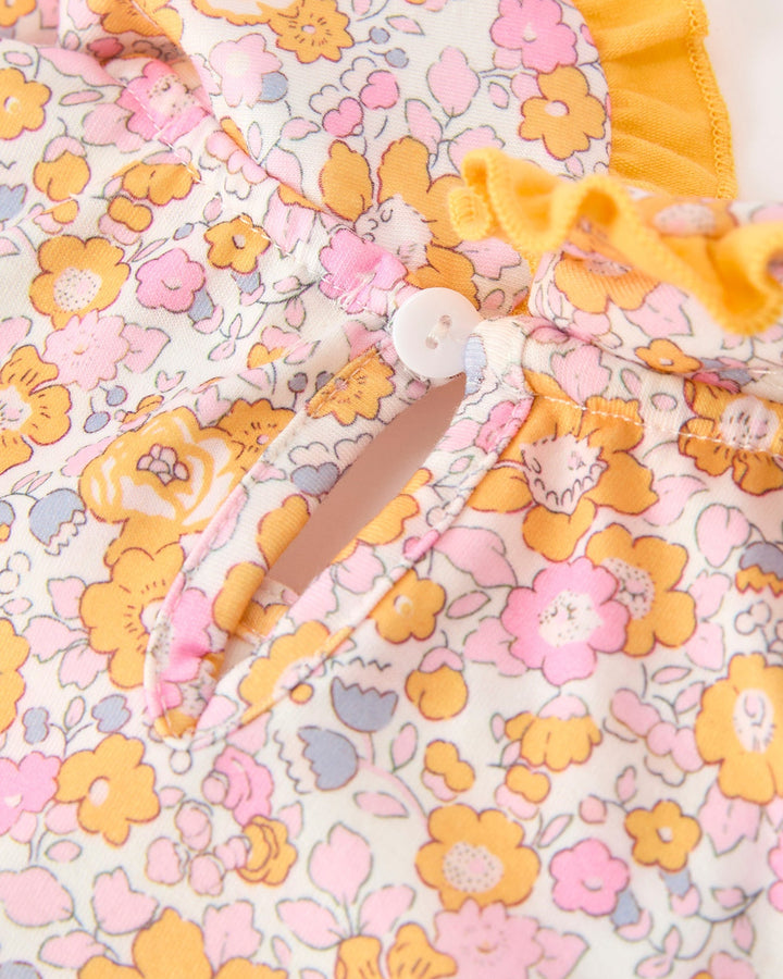 Girls floral dress fabric close-up with orange, pink and yellow flower pattern