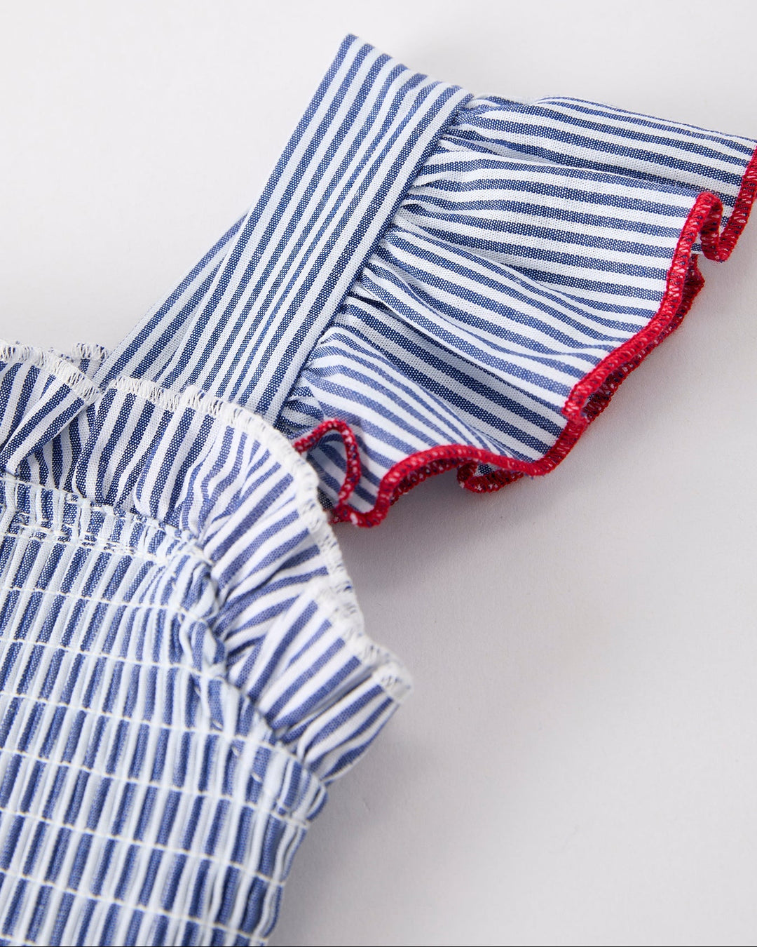 Blue and white striped dress with red trim on a light gray background