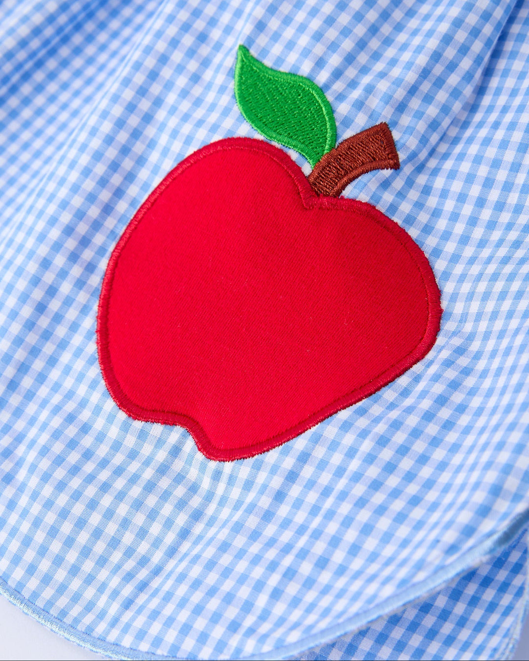 Red apple patch on a blue checkered shirt