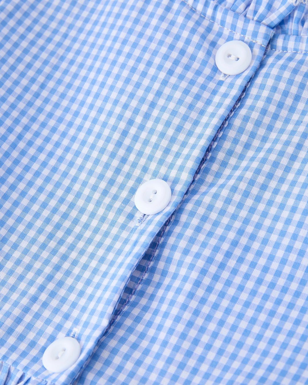 Close-up of a blue and white checkered shirt with buttons.