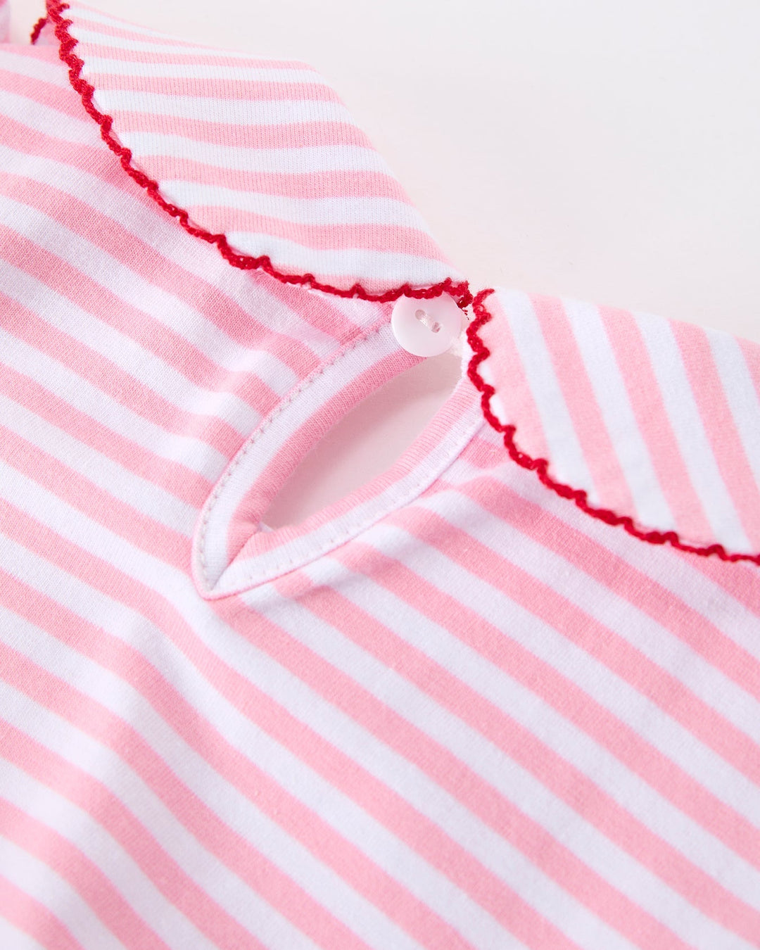 Close-up of a pink and white striped garment with a scalloped edge.