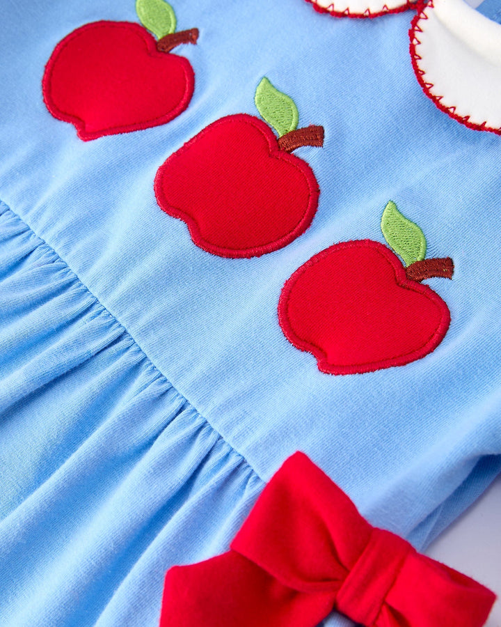 Blue dress with red apple appliqués and a large red bow on a light blue background