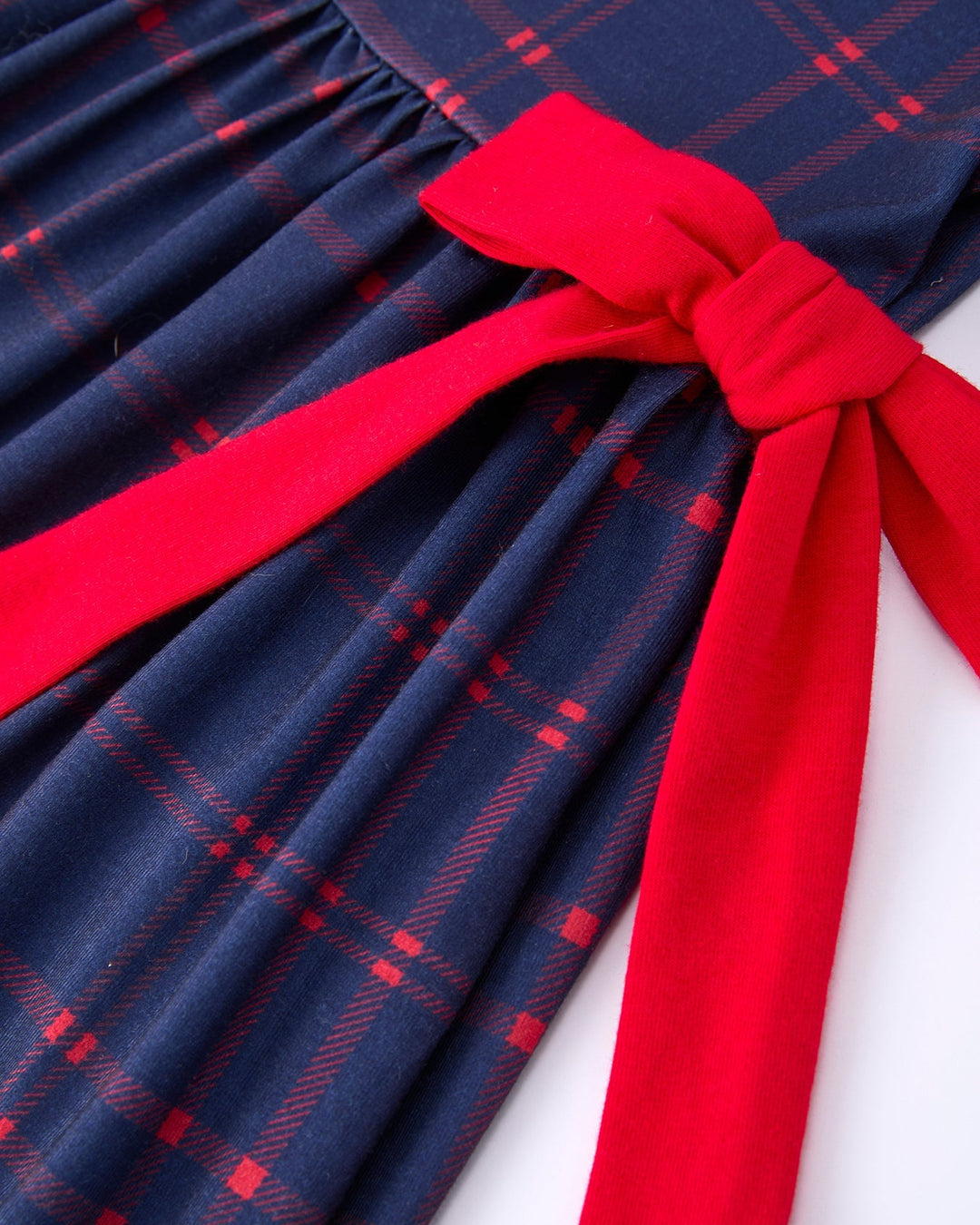 Navy blue plaid dress with a large red bow on a white background