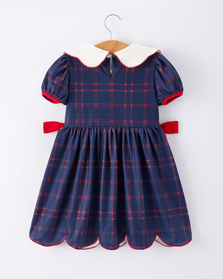 Navy plaid dress with white collar and red accents on a hanger against a white background