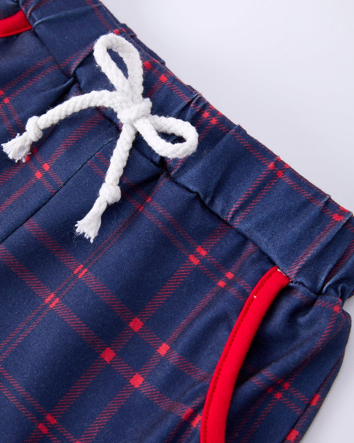 Close-up of blue plaid shorts with red accents and a white drawstring on a white background.