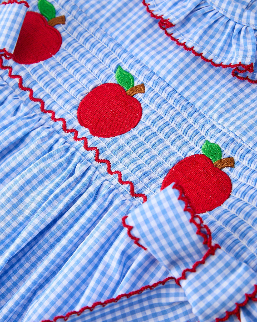 Blue checkered fabric with red apples and green leaves
