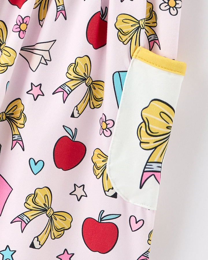 Colorful fabric with bows, apples, and stars on a pink background